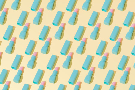 Creative abstract cosmetic makeup lipstick pomade pattern flat lay on pastel yellow background...