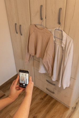 Woman taking pictures of old clothes on phone to sell or donate jackets, concept conscious...