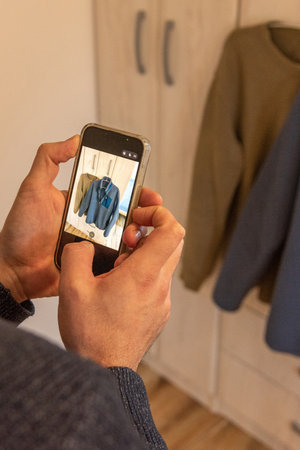 Man taking pictures of old clothes on phone to sell or donate jackets, concept conscious consumption