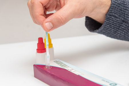 Person doing portable streptococcus bacteria test analysis, patient dips test strip into flask