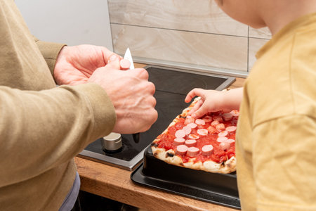 Family man and girl cooking homemade pizza in kitchen, dad and daughter spending time together