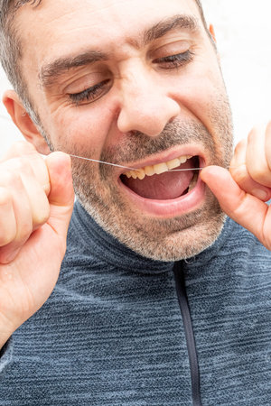 Young man brushing teeth dental floss at home in bathroom, lifestyle daily beauty routineの写真素材