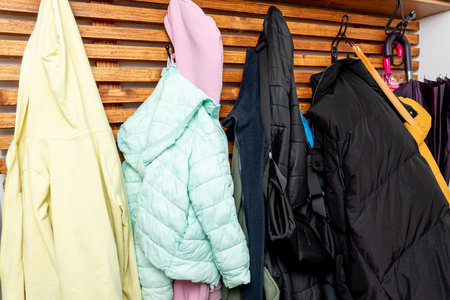 Autumn outerwear jackets and coats hanging on hangers in wooden wardrobe in the hallway