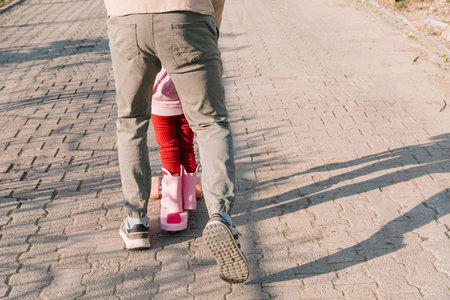 Family dad teaches daughter to ride scooter, active leisure pastime of man and girl toddler