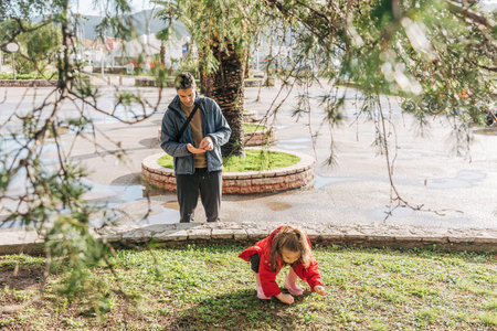 Father and daughter family pick daisies in field, man and toddler girl hold flowers in the...