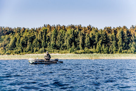 Karelia, Russia, 14 June 202, Fisherman with fishing rod sailing on lake in an inflatable boat