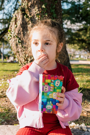 Bar, Montenegro, 2 March 2026, Cute girl toddler eating popcorn from bucket with picture of Labubuのeditorial素材
