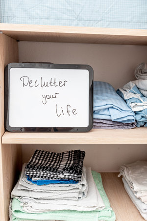 Declutter your life text on board on cloth background, trend clearing space and life of excess conscious consumption