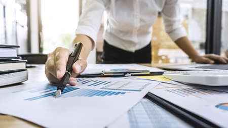 Business woman accountant working and calculating financial data on graph documents, doing finance in workstation.の写真素材