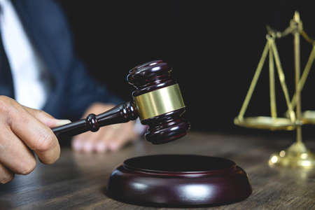 Legal law, advice and justice concept, male counseling lawyer or notary working on a documents and contract papers of the important case and wooden gavel, brass scale in courtroom.の写真素材