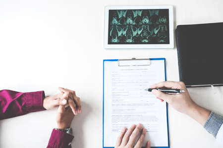Doctor consulting with patient examining X-Ray film for patient, presenting results about the problem and recommend treatment method, Healthcare and medical concept.の写真素材