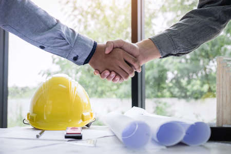 Shaking hands of collaboration, Construction engineering or architect discuss a blueprint while checking information on drawing and sketching, meeting for architectural project of partner.の写真素材