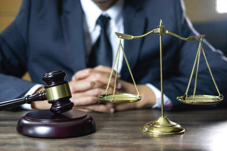 Legal law, advice and justice concept, male counseling lawyer or notary working on a documents and contract papers of the important case and wooden gavel, brass scale in courtroom.の写真素材