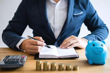 Coin stacks for step up growing business to profit and saving with piggy bank, businessman working with documents and calculator, Saving money for future concept.の写真素材