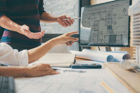 Image of engineer or architect partner meeting for working with architectural project, drawing and sketching for inspection architectural project on blueprint at workspace.の写真素材