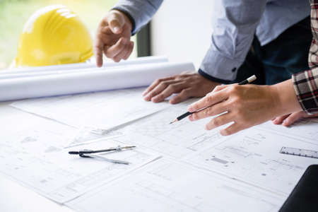 Construction engineering or architect discuss a blueprint while checking information on drawing and sketching meeting for architectural project in work site.の写真素材