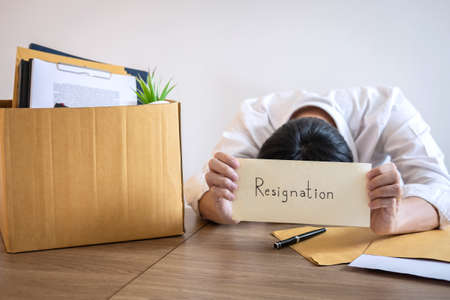 Stressed businessman will being resignation and packing belongings company and files into brown...