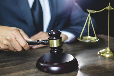 Legal law, advice and justice concept, male lawyer or notary working on a documents and report of the important case and wooden gavel, balance on table in courtroom.の写真素材
