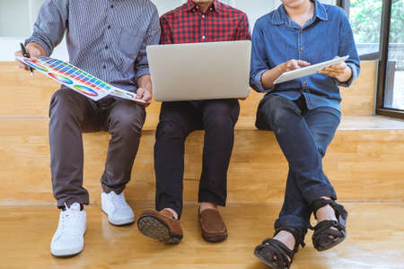 Teamwork of creative designers working on new project and choose color swatch samples for selection coloring on digital graphic tablet with work tools and equipment at workplace.の写真素材