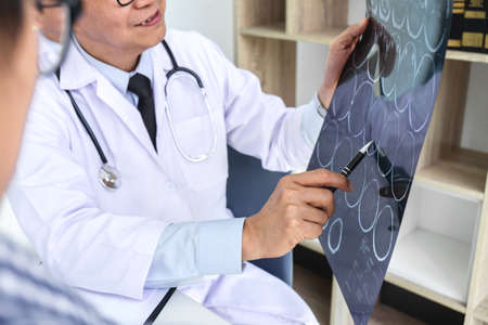 Professor Doctor having conversation with patient and holding x-ray film while discussing explaining...