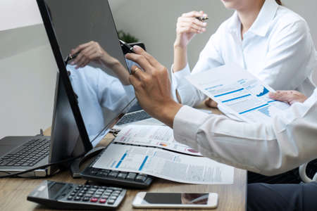Stock exchange market concept, Team of investment trading or stock brokers having a consultation and analyzing with display screen and pointing on the data presented and deal on a stock exchange.の写真素材
