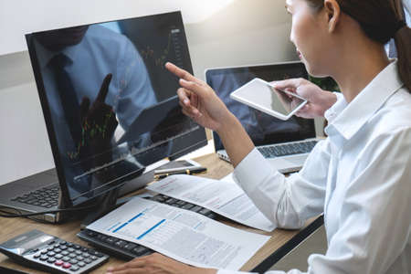 Stock exchange market concept, Team of investment trading or stock brokers having a consultation and analyzing with display screen and pointing on the data presented and deal on a stock exchange.の写真素材