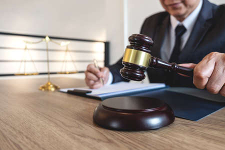 Legal law, advice and justice concept, counselor lawyer or notary working on a documents and report of the important case and wooden gavel, brass scale on table in courtroom.の写真素材