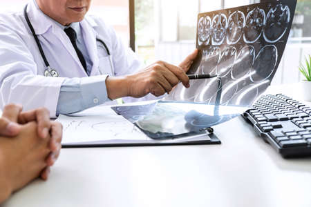 Professor Doctor having conversation with patient and holding x-ray film while discussing explaining her symptoms or counsel diagnosis health, healthcare and assistance concept.の写真素材