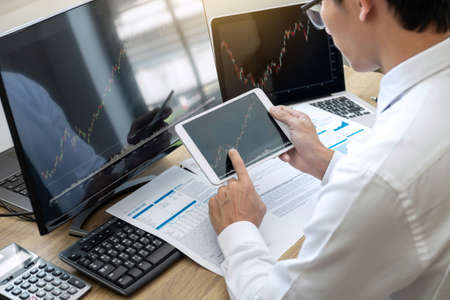 Stock exchange market concept, stock broker looking at graph working and analyzing with display...