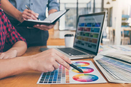 Teamwork of young creative designers working on project together and choose color swatch samples for...
