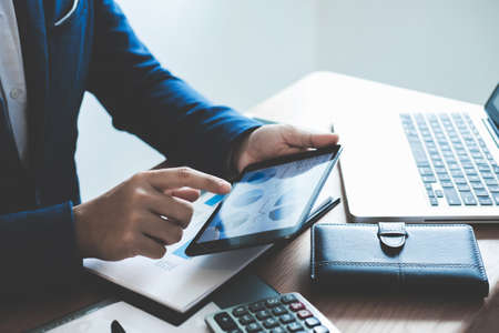 Businessman hands using text information on digital tablet to analyze financial statistical chart...