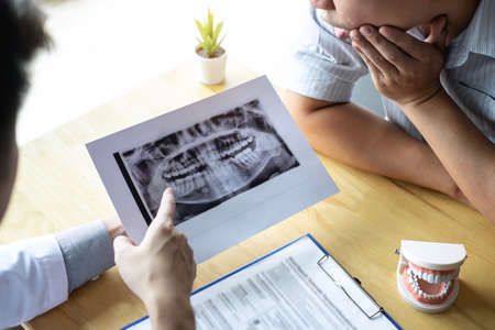 Image of doctor or dentist presenting with tooth x-ray film recommend patient in the treatment of...