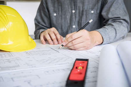 Construction engineering or architect hands working on blueprint inspection in workplace, while checking information drawing and sketching for architecture project working.の写真素材