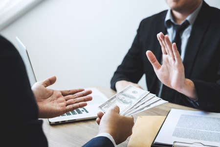 Anti bribery and corruption concept, Business man refusing and don't receive money banknote offered from business people to accept agreement contract of investment deal.の写真素材