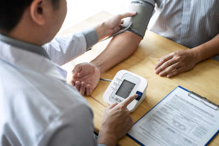 Doctor using a measuring blood pressure checking patient with examining, presenting results symptom...