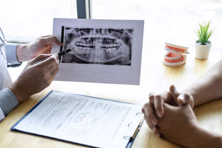 Image of doctor or dentist presenting with tooth x-ray film recommend patient in the treatment of...