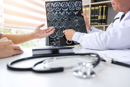Professor Doctor having conversation with patient and holding x-ray film while discussing explaining symptoms or counsel diagnosis health, healthcare and assistance concept.の写真素材