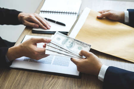Dishonest cheating in business illegal money, Business man giving bribe money in business people to accept agreement contract of investment deal, Bribery and corruption concept.の写真素材