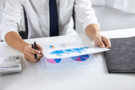 Businessman accountant working audit and calculating expense financial data on graph documents, doing finance in workplace.の写真素材