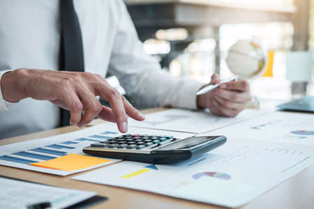 Businessman accountant working analyzing and calculating expense financial annual financial report balance sheet statement, doing finance making notes on report.の写真素材