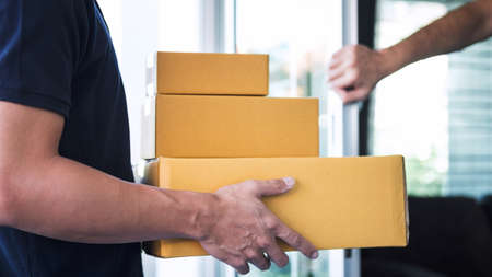 Home owner open door to delivery man standing with parcels in hands outdoors, Home delivery service...