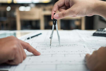 Team of engineering or architect meeting and discussing on blueprint and building model while checking information on sketching for architectural project.の写真素材