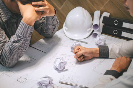 Team of construction engineering or architect partner discuss a blueprint while checking information on drawing and sketching meeting for architectural project with engineering equipment tool.の写真素材