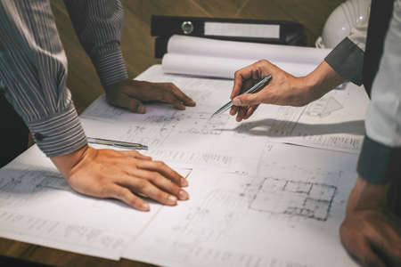 Team of construction engineering or architect partner discuss a blueprint while checking information on drawing and sketching meeting for architectural project with engineering equipment tool.の写真素材