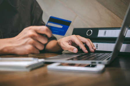 Businessman holding credit card and typing on laptop for online shopping and payment makes a...