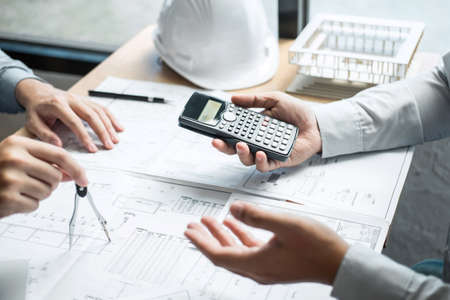 Construction engineering or architect discussing a blueprint and building model while checking information on sketching meeting for architectural project in work site.の写真素材