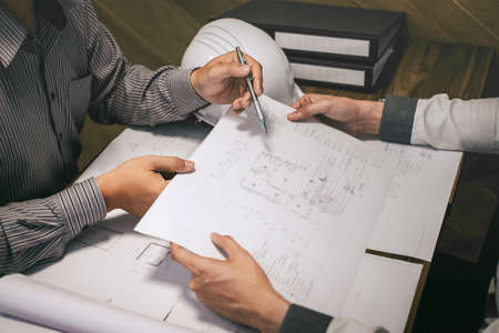 Team of construction engineering or architect partner discuss a blueprint while checking information...