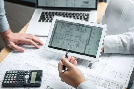 Team of engineering or architect meeting and discussing on blueprint and building model while checking information on sketching for architectural project.の写真素材
