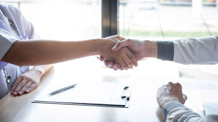 Doctor having shaking hands to congrats with patient after recommend treatment while discussing explaining his symptoms and counsel diagnosis health, healthcare and assistance concept.の写真素材