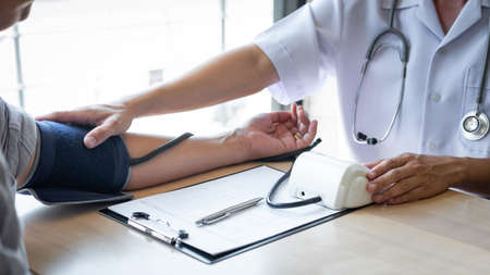 Doctor using a measuring blood pressure checking patient with examining, presenting results symptom and recommend treatment method, Healthcare and medical concept.の写真素材